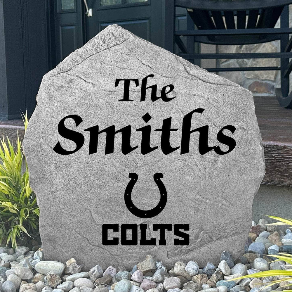 Custom Indianapolis Colts Name Stone displayed in a landscaped flower bed, showcasing personalized family lettering and officially licensed team artwork. This decorative outdoor stone creates a striking focal point for Colts fans and outdoor living spaces.