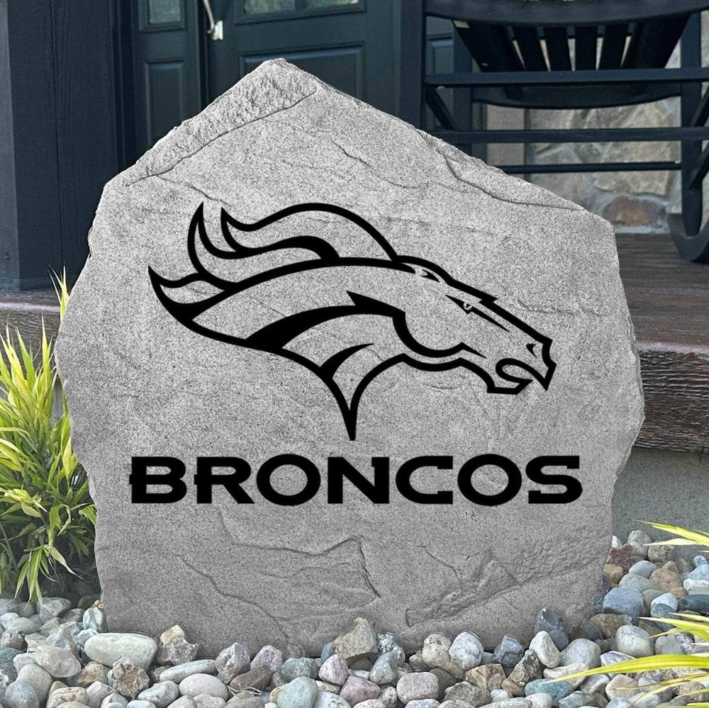 Custom Denver Broncos Logo Stone displayed in a landscaped flower bed, showcasing officially licensed team artwork permanently engraved into the stone. This outdoor accent creates a bold focal point for Broncos fans and outdoor living spaces.
