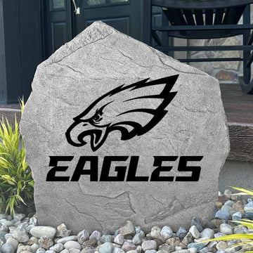 Custom Philadelphia Eagles Logo Stone displayed in a landscaped flower bed, showcasing officially licensed team artwork permanently engraved into the stone. This outdoor accent creates a bold focal point for Eagles fans and outdoor living spaces.
