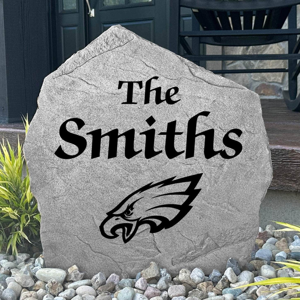 Custom Philadelphia Eagles Name Stone displayed in a landscaped flower bed, showcasing personalized family lettering and officially licensed team artwork. This decorative outdoor stone creates a striking focal point for Eagles fans and outdoor living spaces.