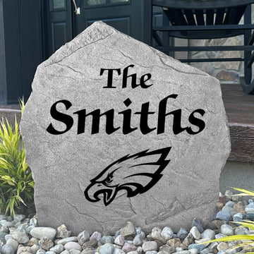 Custom Philadelphia Eagles Name Stone displayed in a landscaped flower bed, showcasing personalized family lettering and officially licensed team artwork. This decorative outdoor stone creates a striking focal point for Eagles fans and outdoor living spaces.