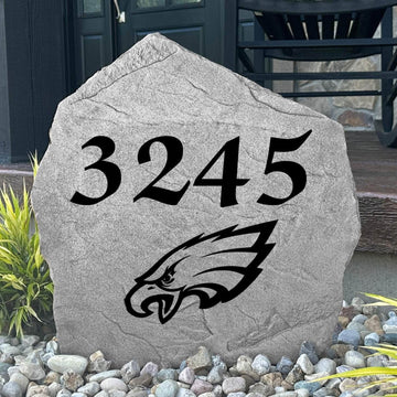 Custom Philadelphia Eagles Address Stone displayed in a landscaped flower bed with personalized house numbers and officially licensed team artwork. This engraved address marker creates a striking focal point for Eagles fans and outdoor living spaces.