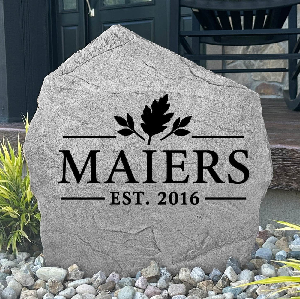 Gray Fall Name Stone personalized MAIERS Est. 2016, displayed in landscape rock by a black front door