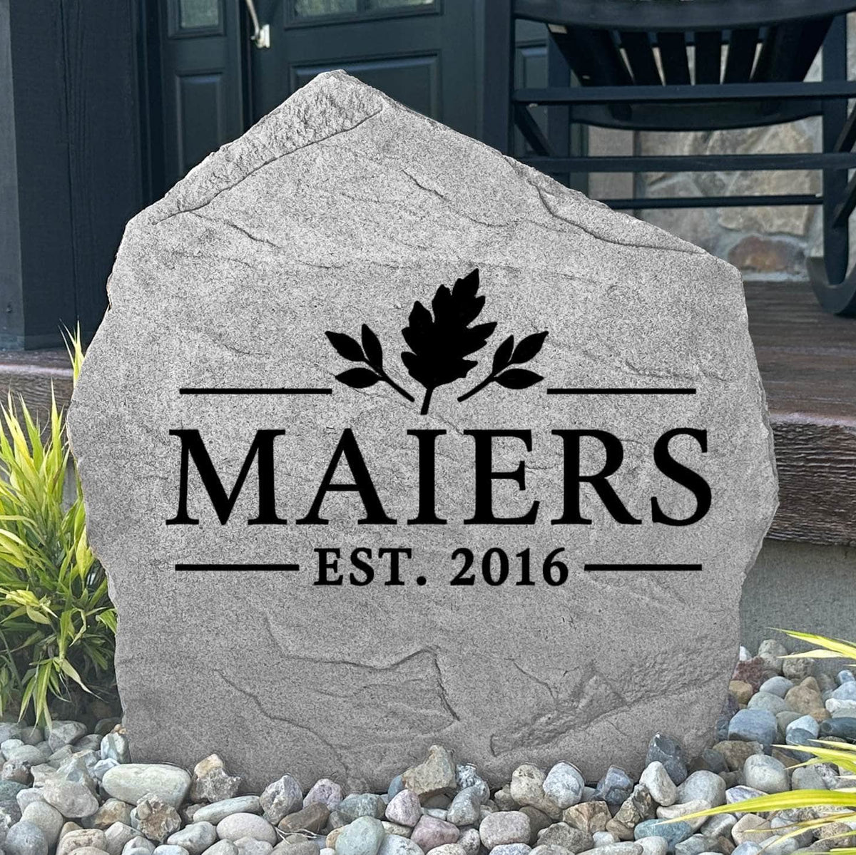 Gray Fall Name Stone personalized MAIERS Est. 2016, displayed in landscape rock by a black front door