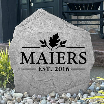 Gray Fall Name Stone personalized MAIERS Est. 2016, displayed in landscape rock by a black front door