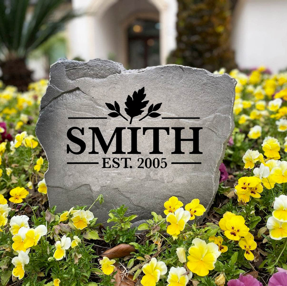 Fall Name Stone engraved SMITH Est. 2005 standing in a flower bed of yellow and purple pansies