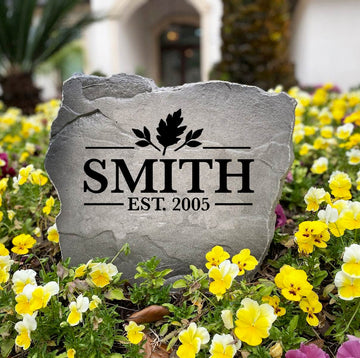 Fall Name Stone engraved SMITH Est. 2005 standing in a flower bed of yellow and purple pansies