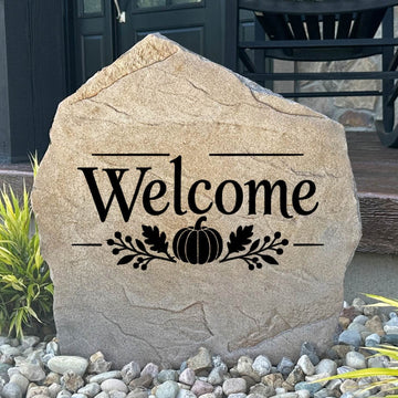 Sandstone Fall Welcome Stone engraved Welcome with a pumpkin and oak leaf design, set in river rock by a front porch