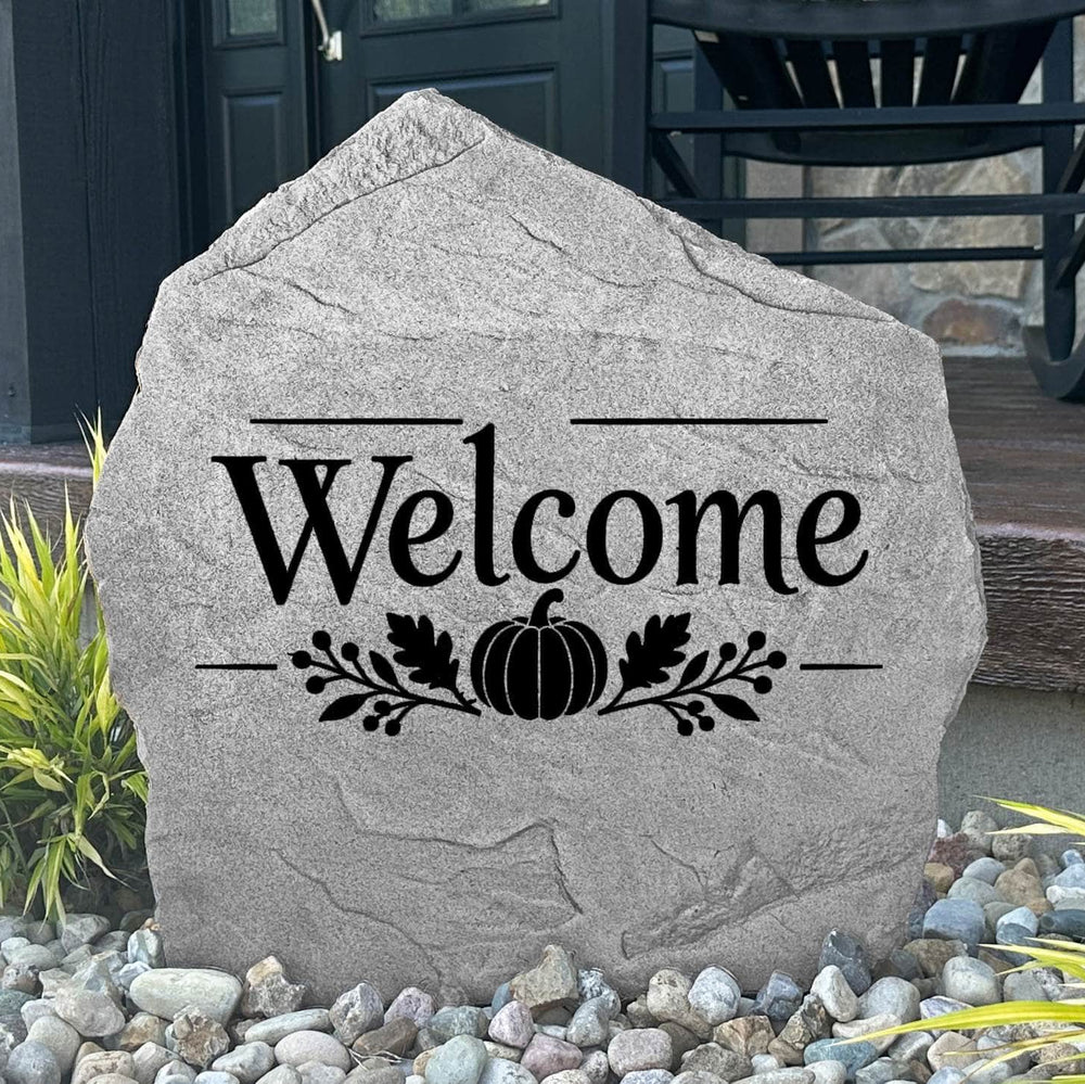 Greystone Fall Welcome Stone with a pumpkin engraving, displayed in landscape rock beside a black front door