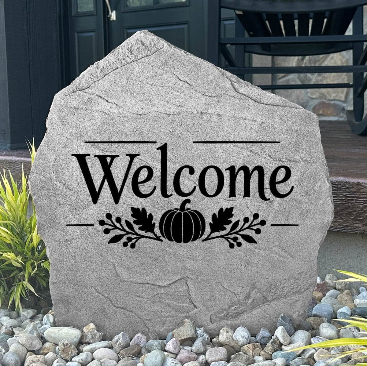 Greystone Fall Welcome Stone with a pumpkin engraving, displayed in landscape rock beside a black front door