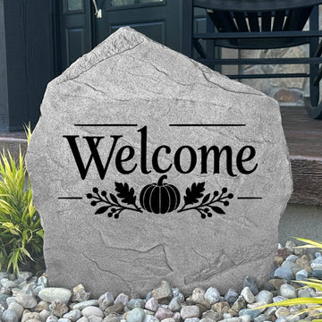 Greystone Fall Welcome Stone with a pumpkin engraving, displayed in landscape rock beside a black front door