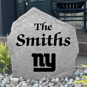 Custom New York Giants Name Stone displayed in a landscaped flower bed, showcasing personalized family lettering and officially licensed team artwork. This decorative outdoor stone creates a striking focal point for Giants fans and outdoor living spaces.