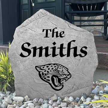 Custom Jacksonville Jaguars Name Stone displayed in a landscaped flower bed, showcasing personalized family lettering and officially licensed team artwork. This decorative outdoor stone creates a striking focal point for Jaguars fans and outdoor living spaces.