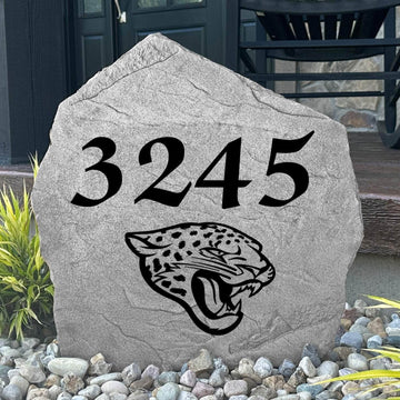 Custom Jacksonville Jaguars Address Stone displayed in a landscaped flower bed with personalized house numbers and officially licensed team artwork. This engraved address marker creates a striking focal point for Jaguars fans and outdoor living spaces.