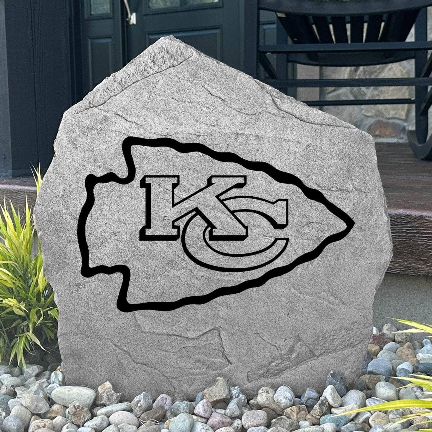 Custom Kansas City Chiefs Logo Stone displayed in a landscaped flower bed, showcasing officially licensed team artwork permanently engraved into the stone. This outdoor accent creates a bold focal point for Chiefs fans and outdoor living spaces.