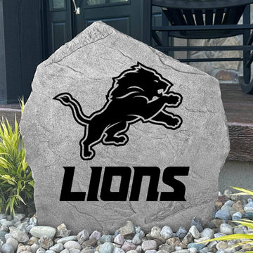 Custom Detroit Lions Logo Stone displayed in a landscaped flower bed, showcasing officially licensed team artwork permanently engraved into the stone. This outdoor accent creates a bold focal point for Lions fans and outdoor living spaces.