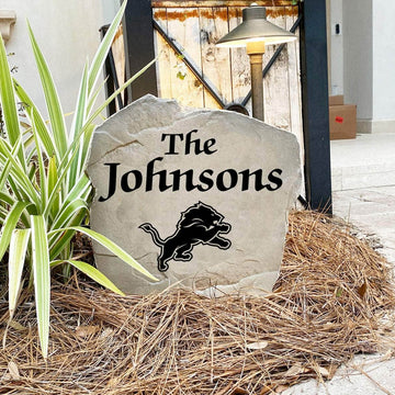 Custom Detroit Lions Name Stone displayed in a landscaped flower bed, showcasing personalized family lettering and officially licensed team artwork. This decorative outdoor stone creates a striking focal point for Lions fans and outdoor living spaces.