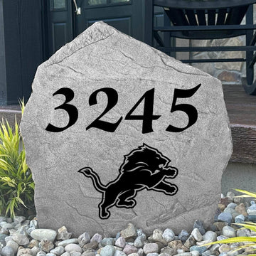 Custom Detroit Lions Address Stone displayed in a landscaped flower bed with personalized house numbers and officially licensed team artwork. This engraved address marker creates a striking focal point for Lions fans and outdoor living spaces.