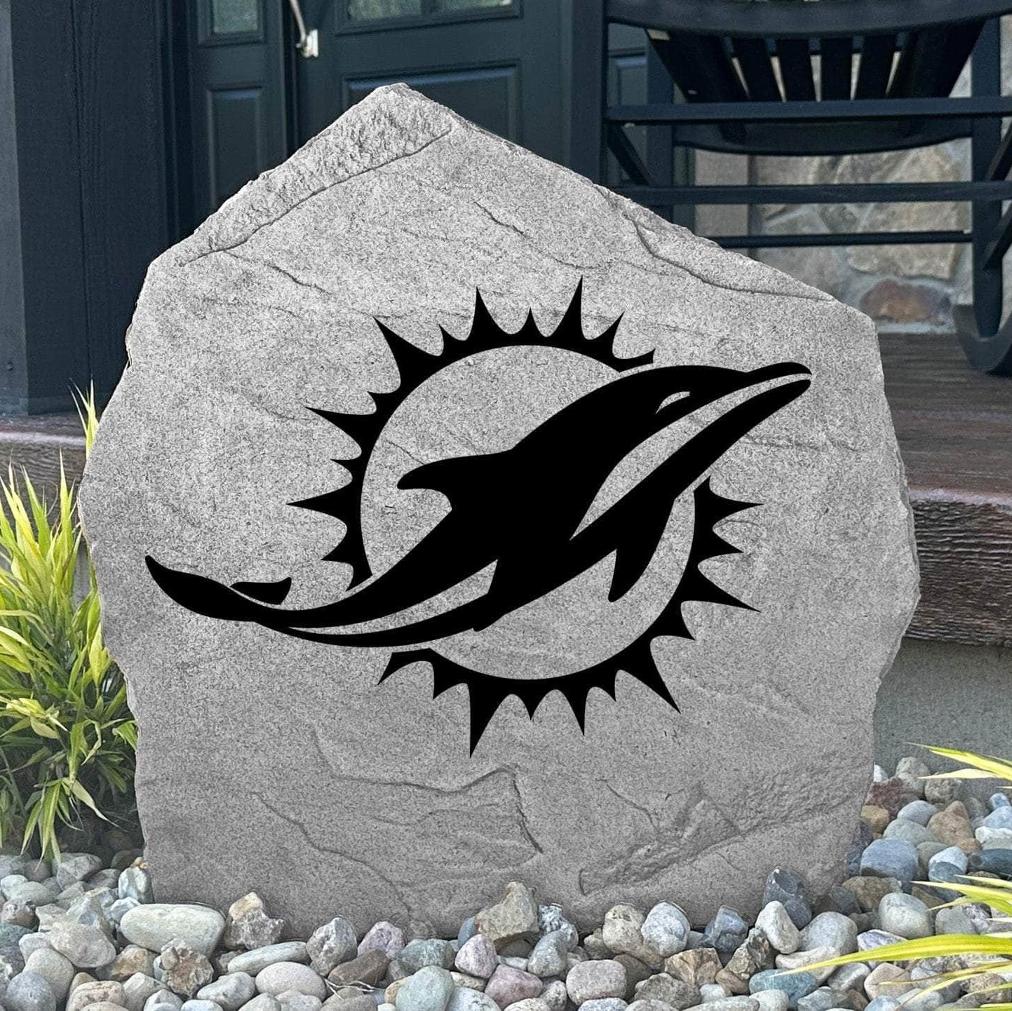 Custom Miami Dolphins Logo Stone displayed in a landscaped flower bed, showcasing officially licensed team artwork permanently engraved into the stone. This outdoor accent creates a bold focal point for Dolphins fans and outdoor living spaces.