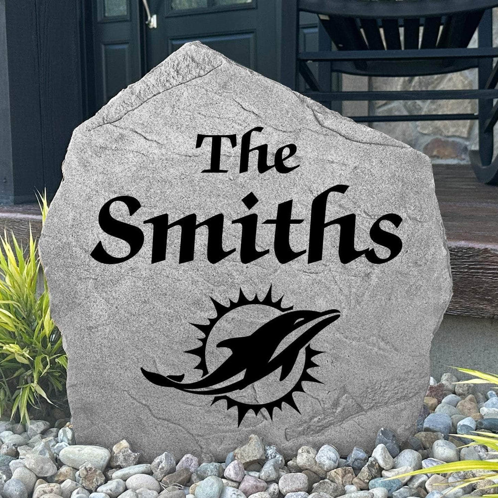Custom Miami Dolphins Name Stone displayed in a landscaped flower bed, showcasing personalized family lettering and officially licensed team artwork. This decorative outdoor stone creates a striking focal point for Dolphins fans and outdoor living spaces.