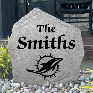 Custom Miami Dolphins Name Stone displayed in a landscaped flower bed, showcasing personalized family lettering and officially licensed team artwork. This decorative outdoor stone creates a striking focal point for Dolphins fans and outdoor living spaces.