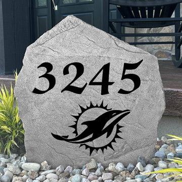 Custom Miami Dolphins Address Stone displayed in a landscaped flower bed with personalized house numbers and officially licensed team artwork. This engraved address marker creates a striking focal point for Dolphins fans and outdoor living spaces.