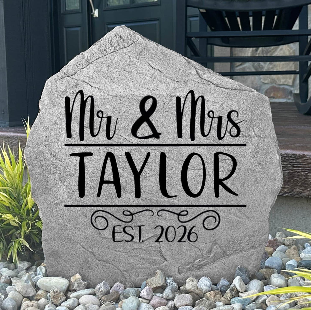 Custom Mr. & Mrs. Name Stone displayed in a landscaped flower bed, showcasing personalized names and wedding-inspired engraving. This decorative garden stone creates a beautiful focal point for newlyweds and family homes.