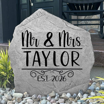 Custom Mr. & Mrs. Name Stone displayed in a landscaped flower bed, showcasing personalized names and wedding-inspired engraving. This decorative garden stone creates a beautiful focal point for newlyweds and family homes.