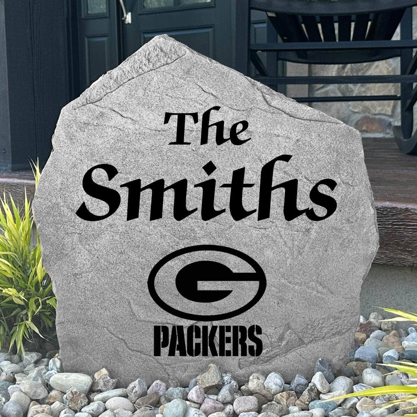 Custom Green Bay Packers Name Stone displayed in a landscaped flower bed, showcasing personalized family lettering and officially licensed team artwork. This decorative outdoor stone creates a striking focal point for Packers fans and outdoor living spaces.