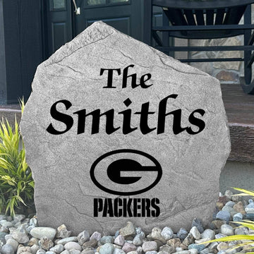 Custom Green Bay Packers Name Stone displayed in a landscaped flower bed, showcasing personalized family lettering and officially licensed team artwork. This decorative outdoor stone creates a striking focal point for Packers fans and outdoor living spaces.