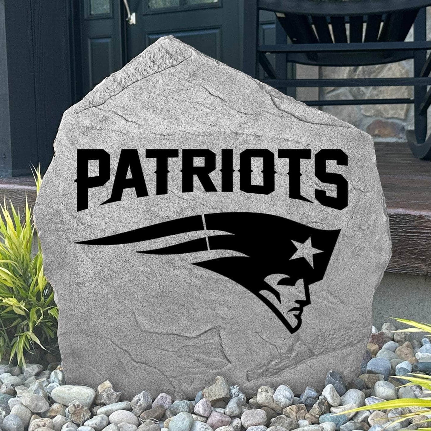 Custom New England Patriots Logo Stone displayed in a landscaped flower bed, showcasing officially licensed team artwork permanently engraved into the stone. This outdoor accent creates a bold focal point for Patriots fans and outdoor living spaces.