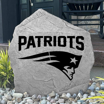 Custom New England Patriots Logo Stone displayed in a landscaped flower bed, showcasing officially licensed team artwork permanently engraved into the stone. This outdoor accent creates a bold focal point for Patriots fans and outdoor living spaces.