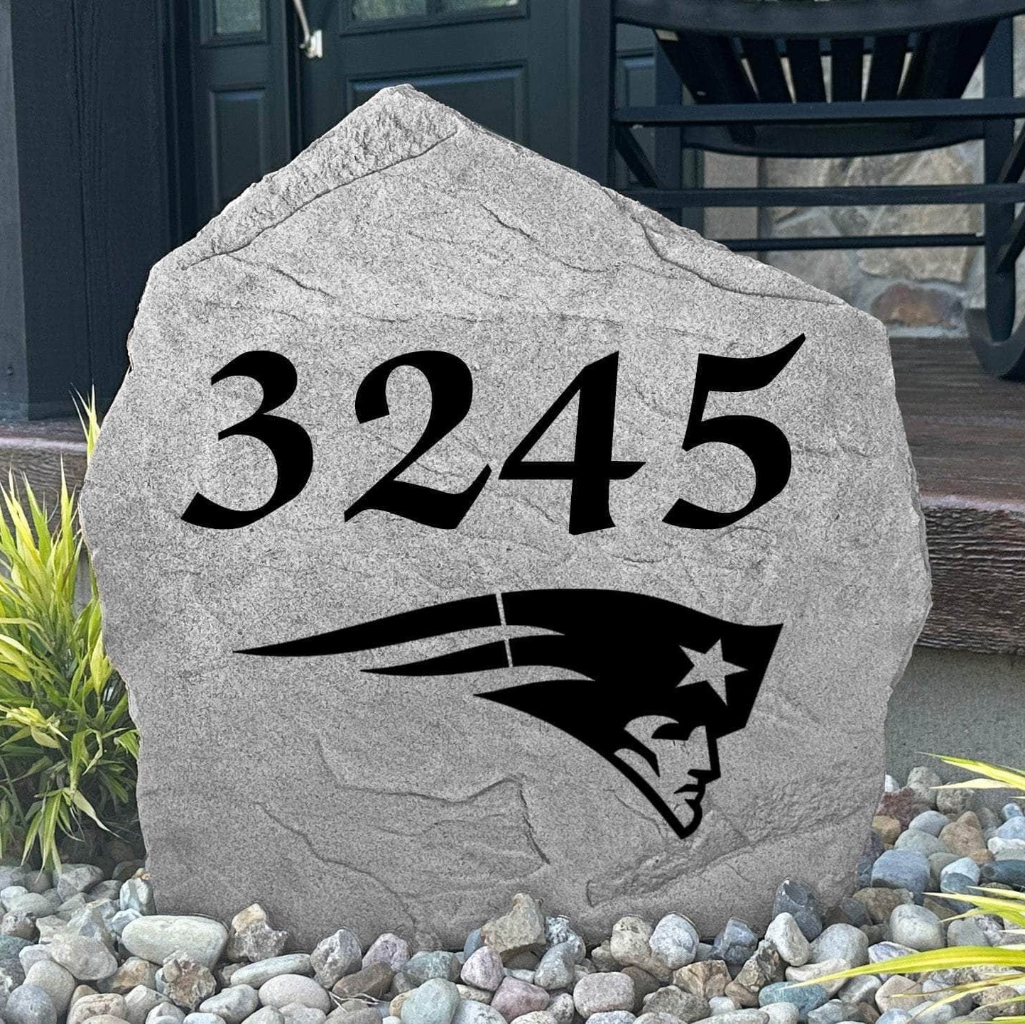 Custom New England Patriots Address Stone displayed in a landscaped flower bed with personalized house numbers and officially licensed team artwork. This engraved address marker creates a striking focal point for Patriots fans and outdoor living spaces.