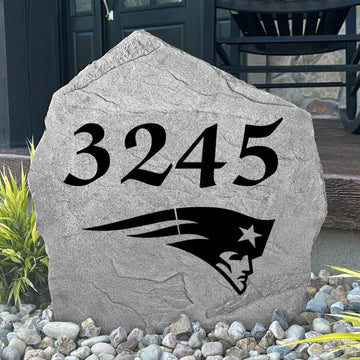 Custom New England Patriots Address Stone displayed in a landscaped flower bed with personalized house numbers and officially licensed team artwork. This engraved address marker creates a striking focal point for Patriots fans and outdoor living spaces.