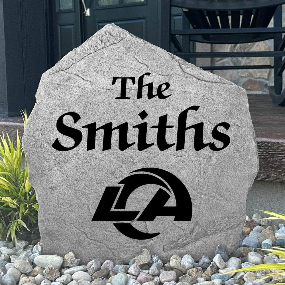 Custom Los Angeles Rams Name Stone displayed in a landscaped flower bed, showcasing personalized family lettering and officially licensed team artwork. This decorative outdoor stone creates a striking focal point for Rams fans and outdoor living spaces.