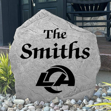 Custom Los Angeles Rams Name Stone displayed in a landscaped flower bed, showcasing personalized family lettering and officially licensed team artwork. This decorative outdoor stone creates a striking focal point for Rams fans and outdoor living spaces.