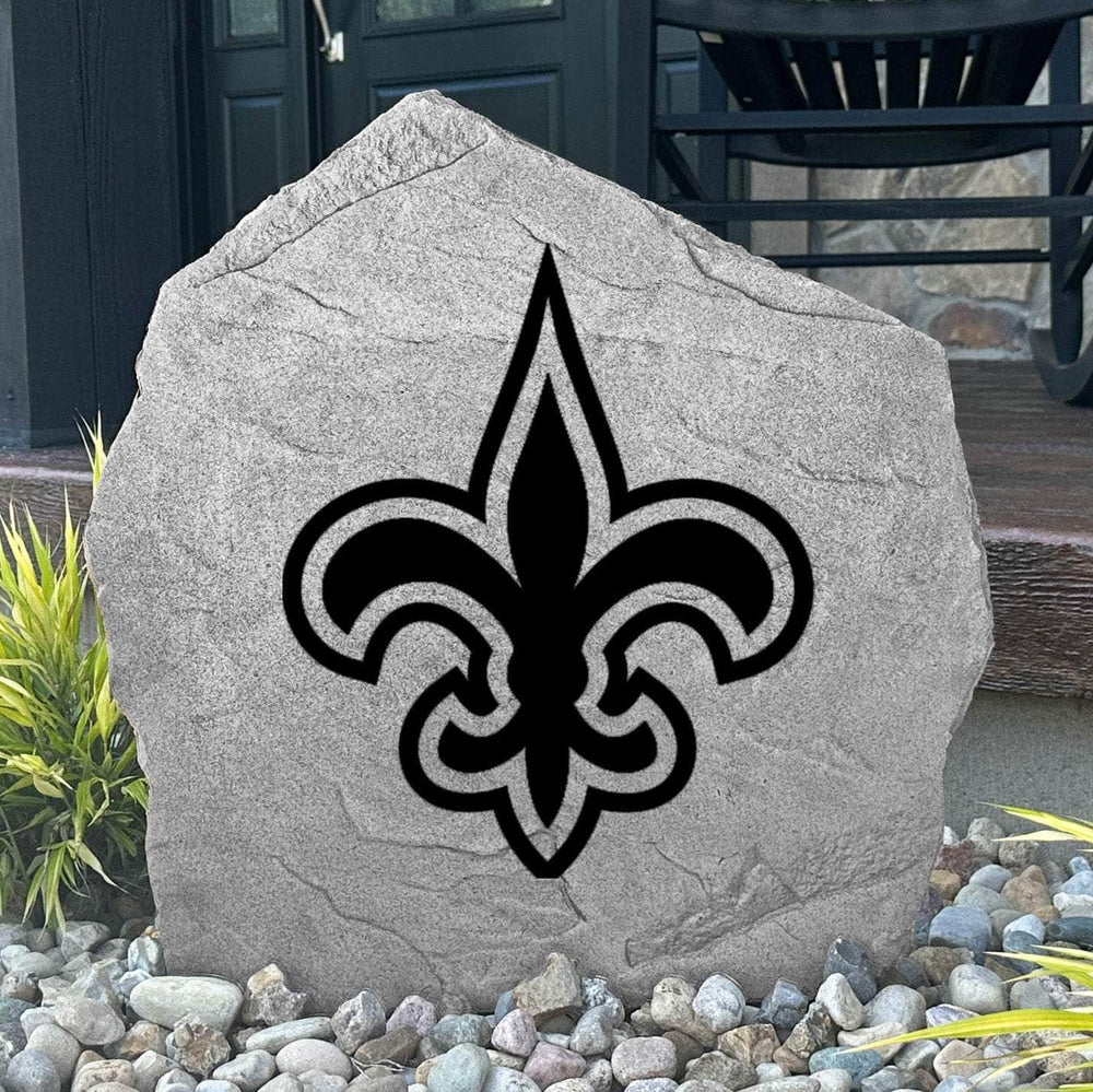 Custom New Orleans Saints Logo Stone displayed in a landscaped flower bed, showcasing officially licensed team artwork permanently engraved into the stone. This outdoor accent creates a bold focal point for Saints fans and outdoor living spaces.