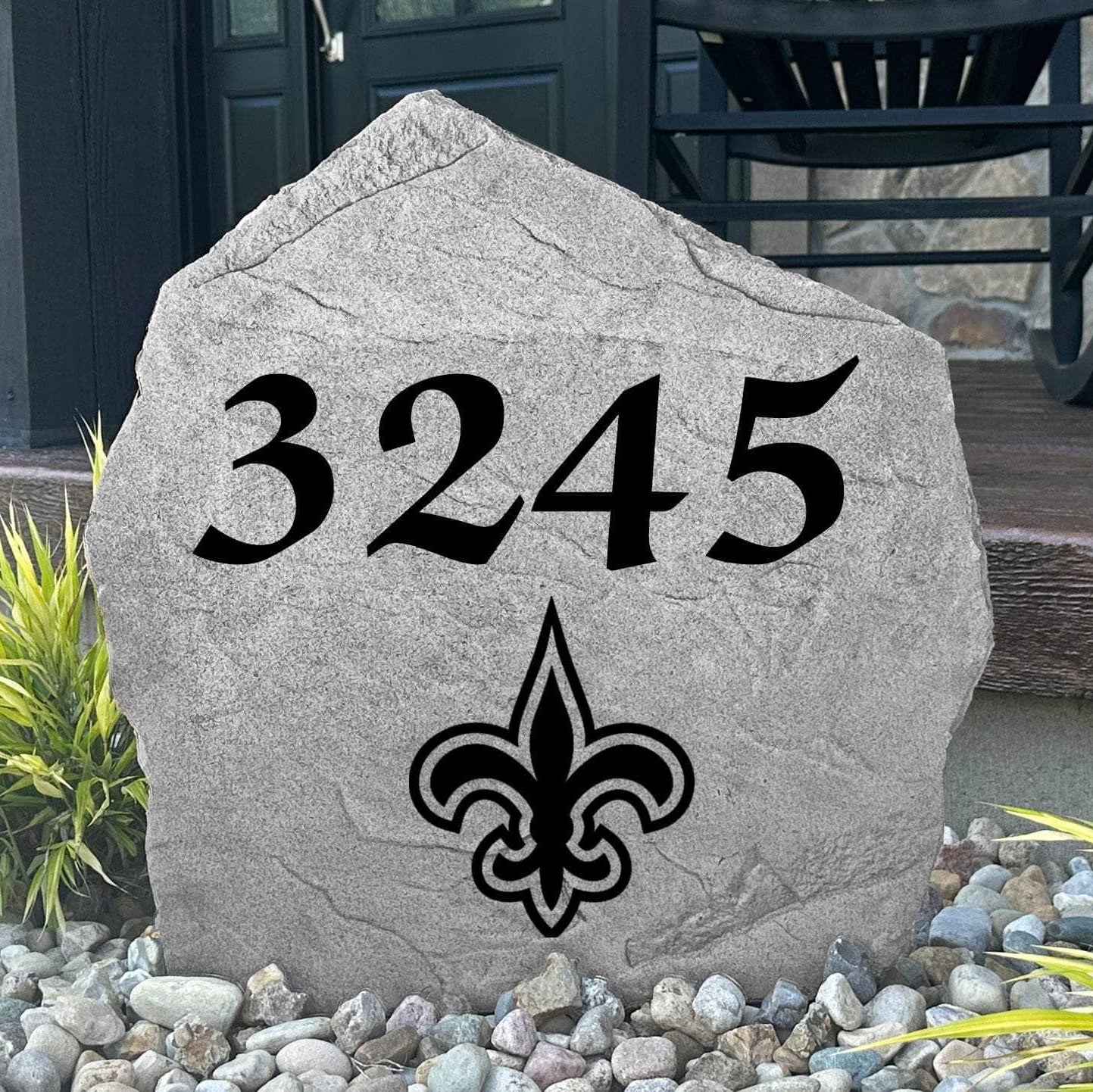 Custom New Orleans Saints Address Stone displayed in a landscaped flower bed with personalized house numbers and officially licensed team artwork. This engraved address marker creates a striking focal point for Saints fans and outdoor living spaces.