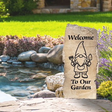 Decorative stone with a garden gnome illustration and 'Welcome To Our Garden' text in a garden setting.