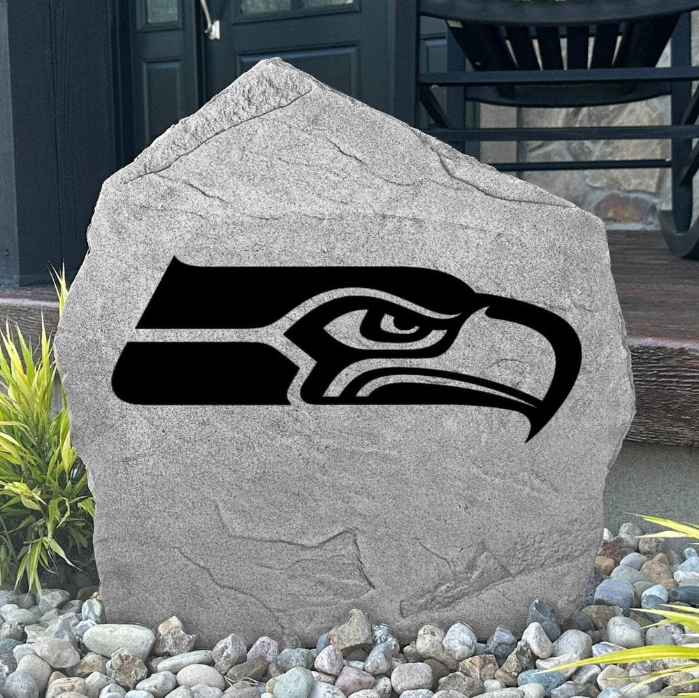 Custom Seattle Seahawks Logo Stone displayed in a landscaped flower bed, showcasing officially licensed team artwork permanently engraved into the stone. This outdoor accent creates a bold focal point for Seahawks fans and outdoor living spaces.
