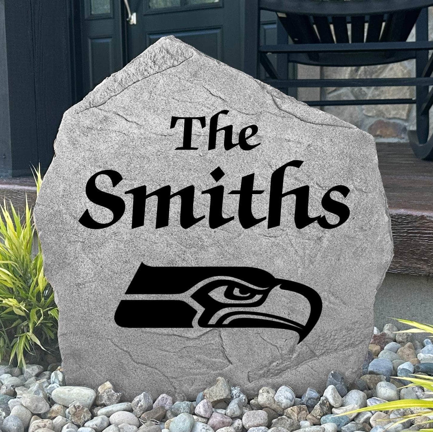 Custom Seattle Seahawks Name Stone displayed in a landscaped flower bed, showcasing personalized family lettering and officially licensed team artwork. This decorative outdoor stone creates a striking focal point for Seahawks fans and outdoor living spaces.