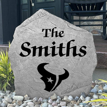 Custom Houston Texans Name Stone displayed in a landscaped flower bed, showcasing personalized family lettering and officially licensed team artwork. This decorative outdoor stone creates a striking focal point for Texans fans and outdoor living spaces.