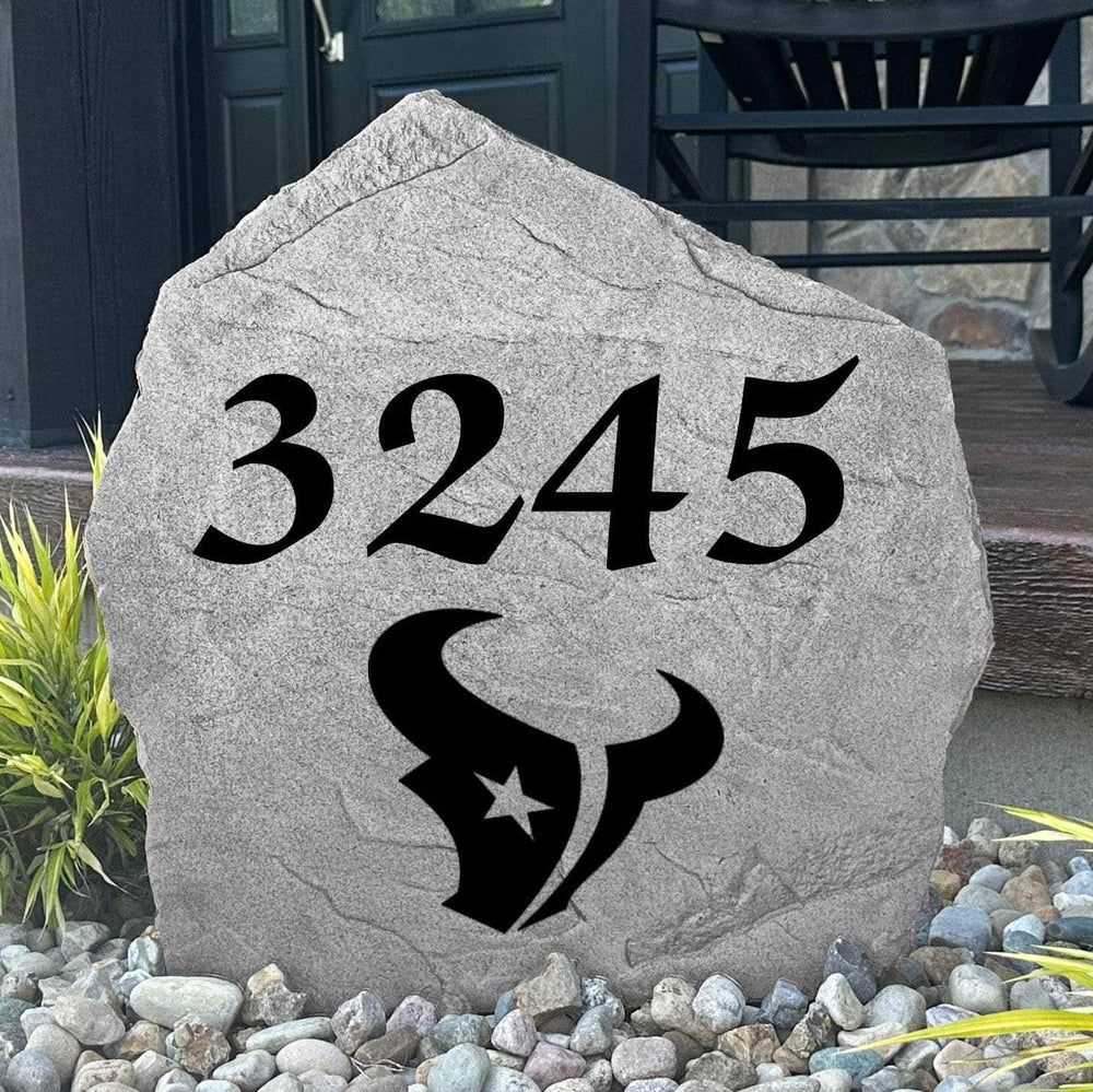 Custom Houston Texans Address Stone displayed in a landscaped flower bed with personalized house numbers and officially licensed team artwork. This engraved address marker creates a striking focal point for Texans fans and outdoor living spaces.