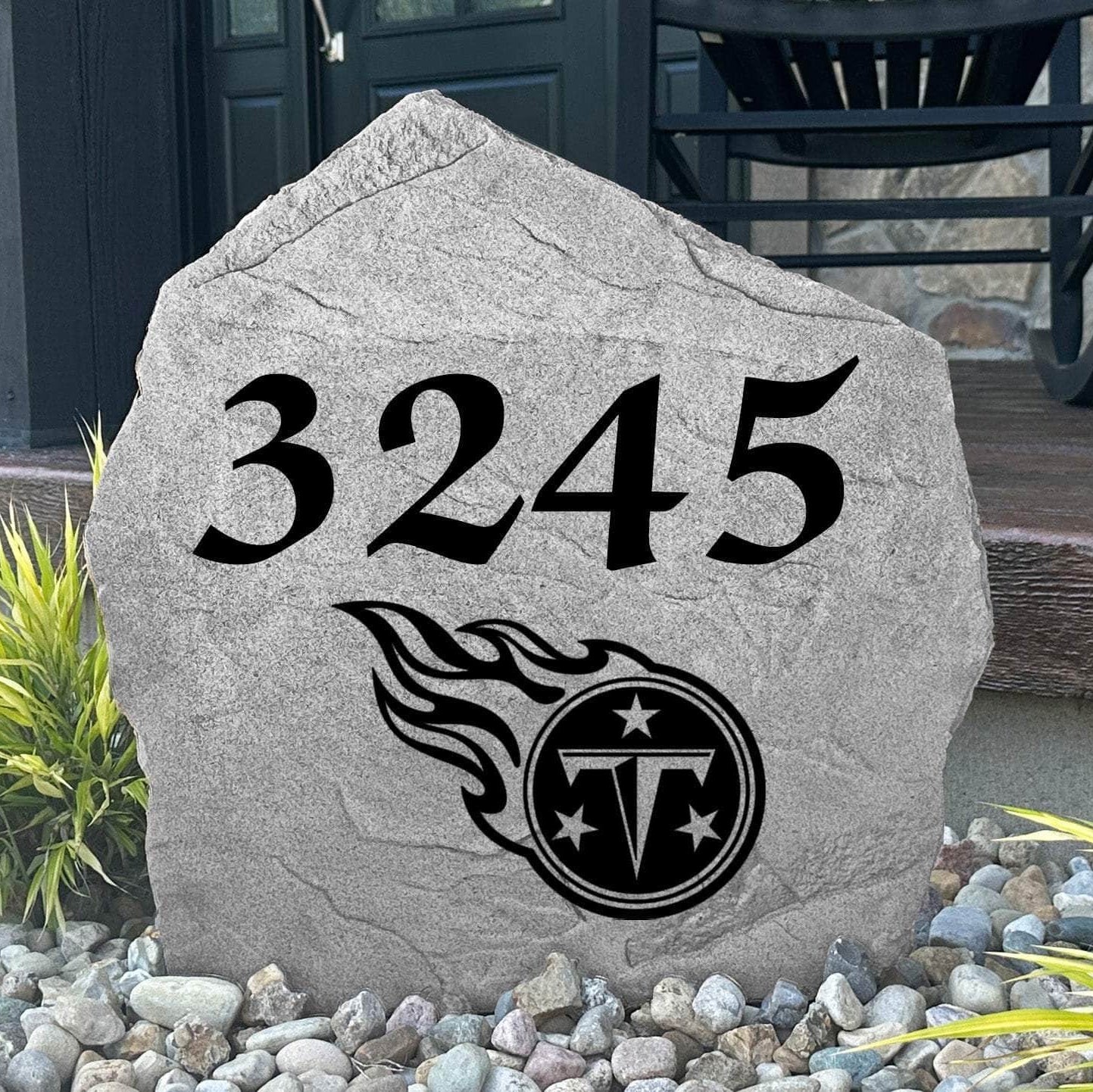 Custom Tennessee Titans Address Stone displayed in a landscaped flower bed with personalized house numbers and officially licensed team artwork. This engraved address marker creates a striking focal point for Titans fans and outdoor living spaces.