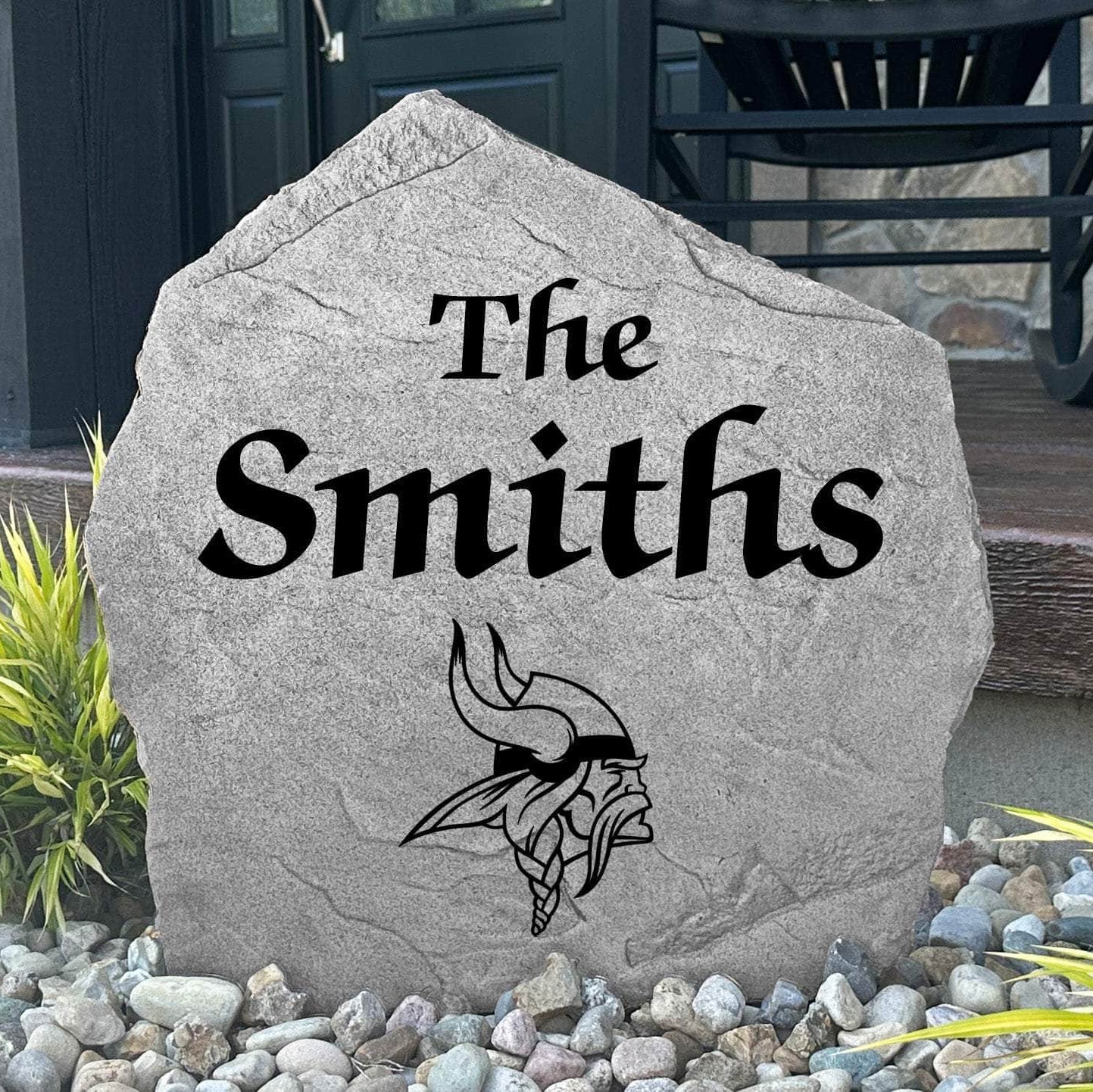 Custom Minnesota Vikings Name Stone displayed in a landscaped flower bed, showcasing personalized family lettering and officially licensed team artwork. This decorative outdoor stone creates a striking focal point for Vikings fans and outdoor living spaces.
