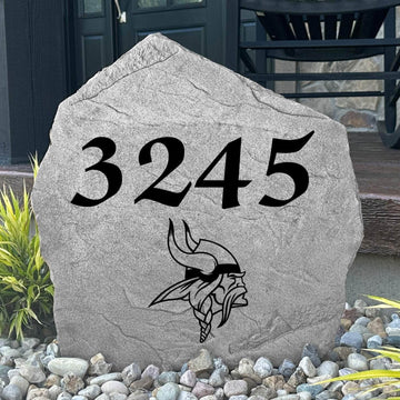 Custom Minnesota Vikings Address Stone displayed in a landscaped flower bed with personalized house numbers and officially licensed team artwork. This engraved address marker creates a striking focal point for Vikings fans and outdoor living spaces.