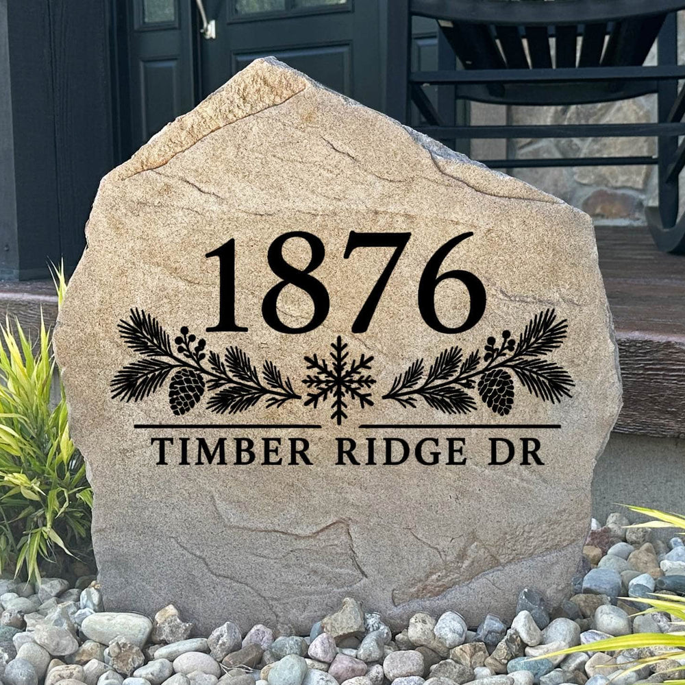 Winter Address Stone engraved 1876 Timber Ridge Dr with pine boughs and a snowflake, set in river rock by a porch