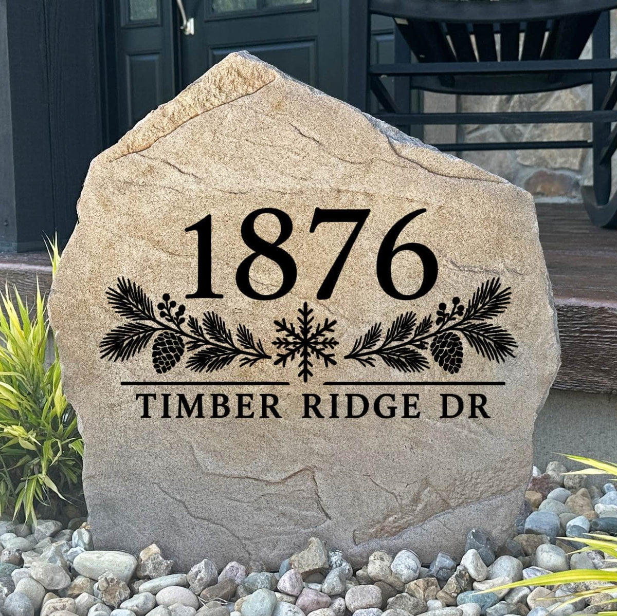 Winter Address Stone engraved 1876 Timber Ridge Dr with pine boughs and a snowflake, set in river rock by a porch