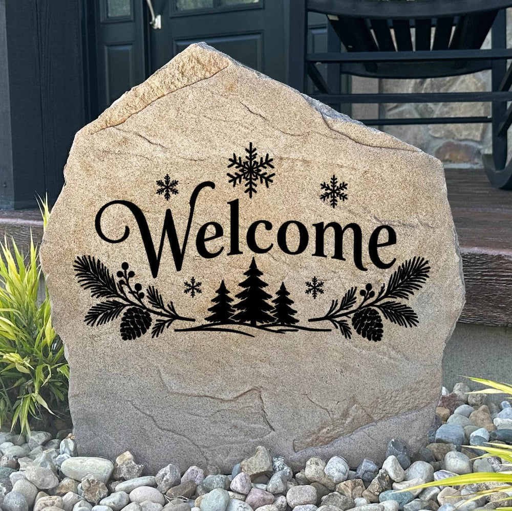 Sandstone Winter Welcome Stone engraved Welcome with pine trees and snowflakes, set in river rock by a porch