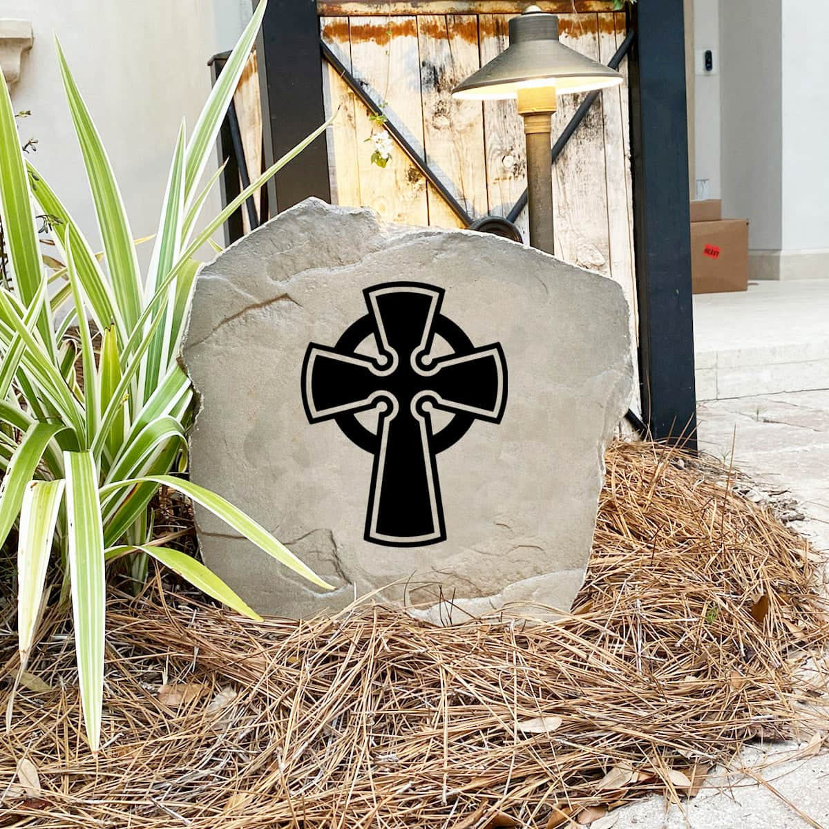 Celtic Cross Stone nestled among colorful flowers and natural greenery, bringing traditional Irish-inspired beauty and spiritual meaning to the landscape. Its weather-resistant design provides lasting charm for outdoor spaces.